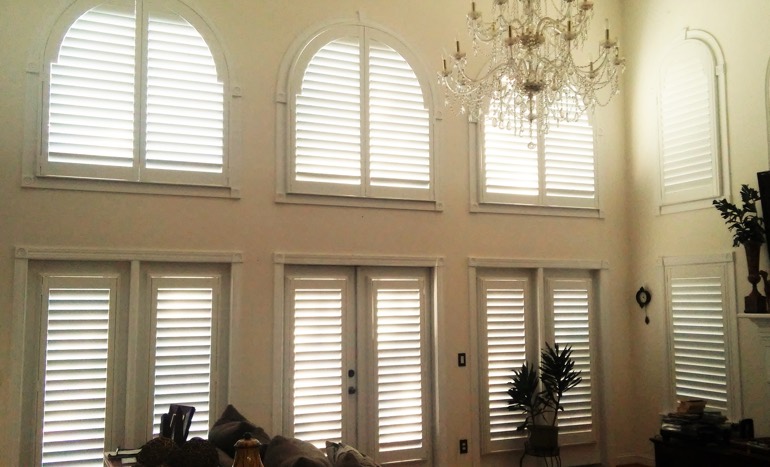 Great room in two-story Detroit home with plantation shutters on high ceiling windows.