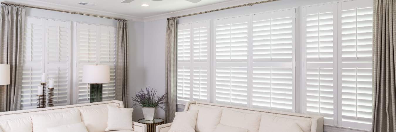 White Polywood shutters on large windows in a great room