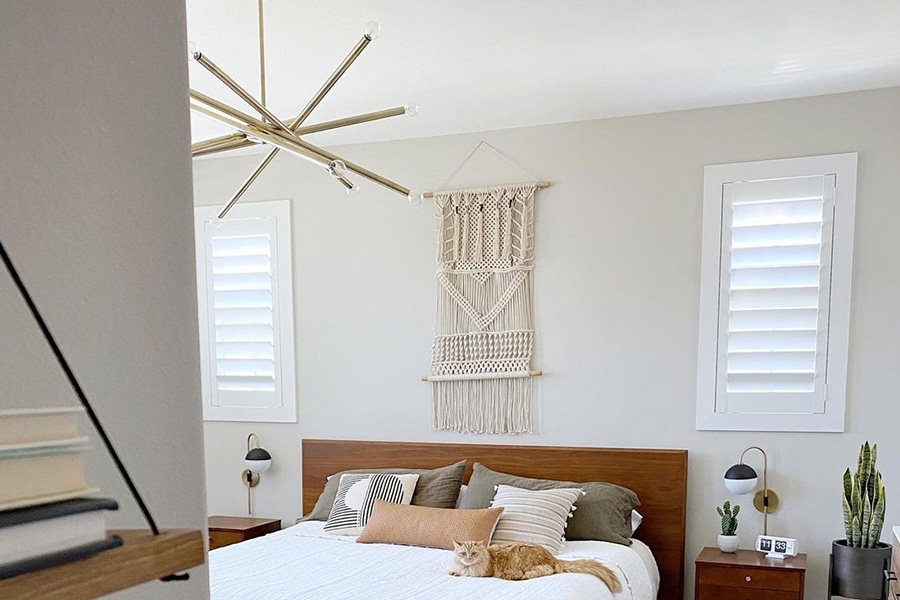 White Polywood shutters in a bedroom with two cats climbing on the bed